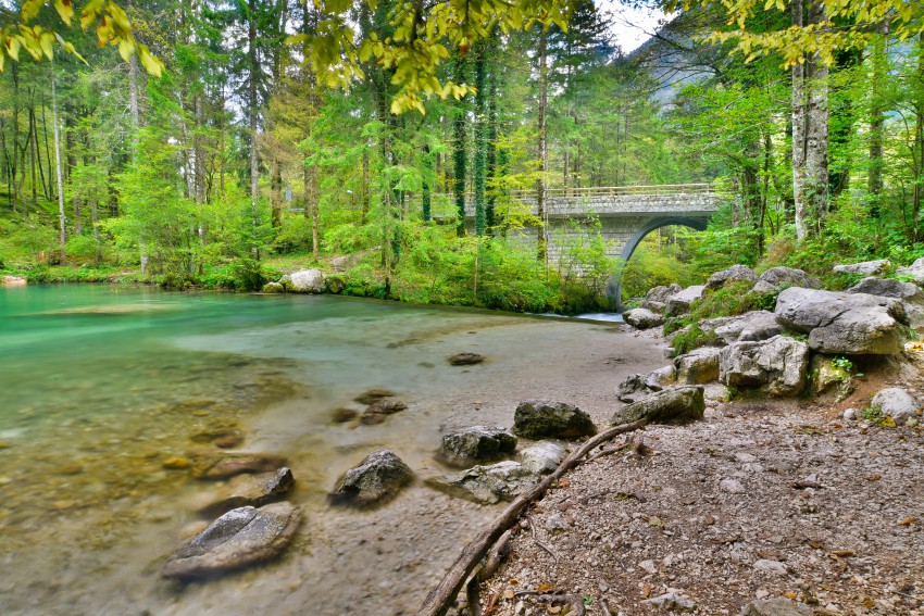 Izvir reke Kamniške Bistrice na koncu Koželjeve poti. V ozadju kamnit most, ki je del poti.