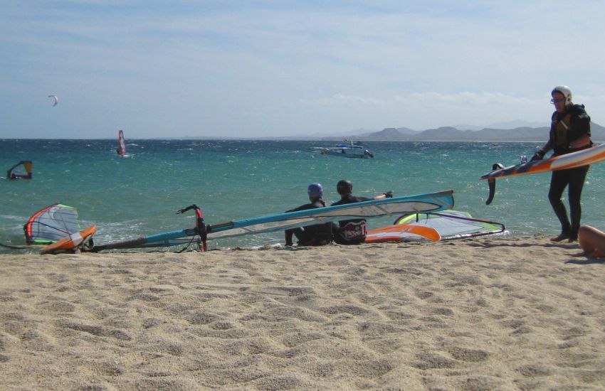 Windsurferji med pripravo opreme - desk z jadri na peščeni plaži v Mehiki s čudovitim razgledom na odprto morje.