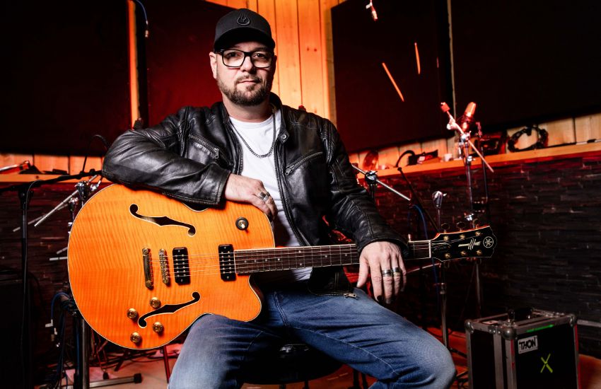 Tomi Meglič, frontman banda Siddharta, pevec, kitarist in glavni tekstopisec sedi v glasbenem studiu s kitaro v roki.