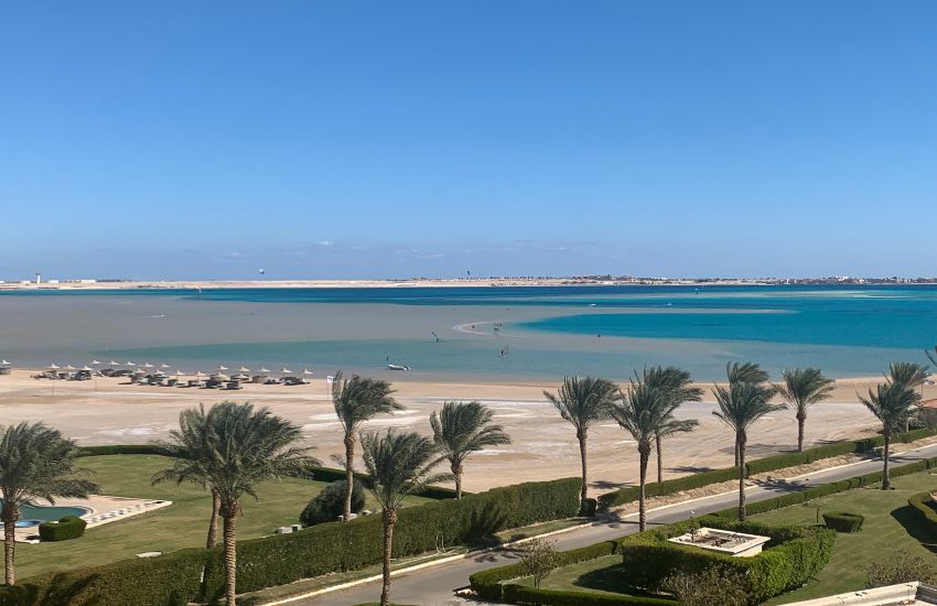 Zaliv Soma bay z mirno turkizno zeleno vodo, peščena plaža z ležalniki, pot na plažo obdana s palmami