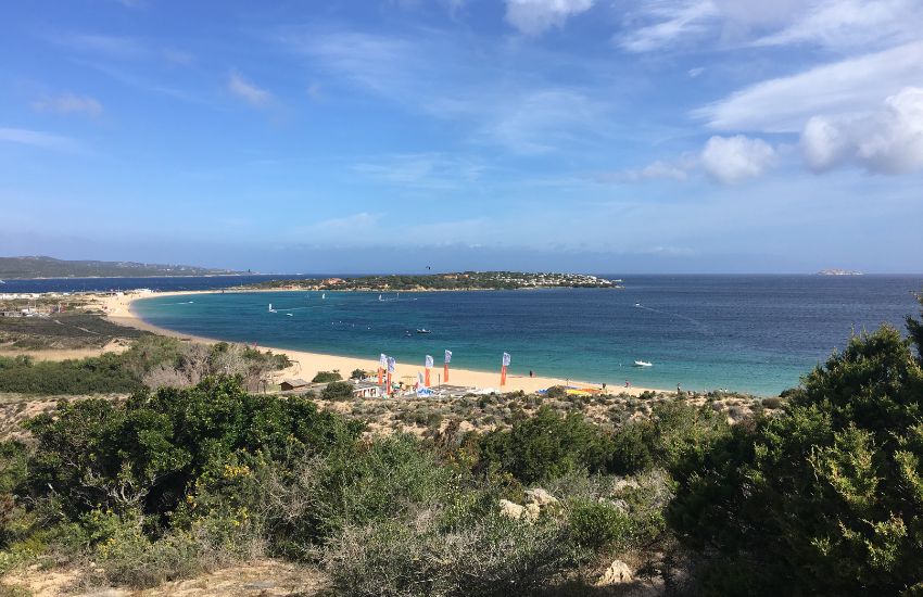 Pogled na zaliv Porto Bello na Sardiniji s peščeno plažo, ki je priljubljen spot za windsurfing.