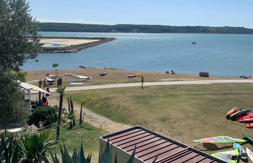 Pogled na windsurferski spot v Seči, vhod v morje je obdan z zelenico.
