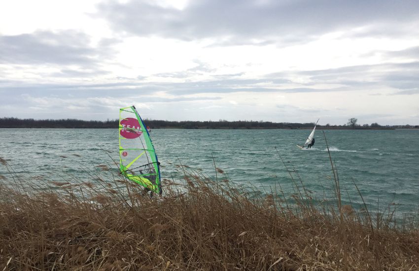 jadro položeno na trato pred jezerom, v ozadju na jezeru jadralci na deski, windsurferji