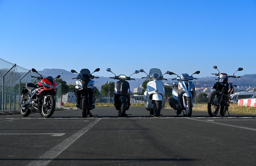 Parkirani motorji in skuterji s prostornino 125 kubikov na poliganu za varno vožnjo.